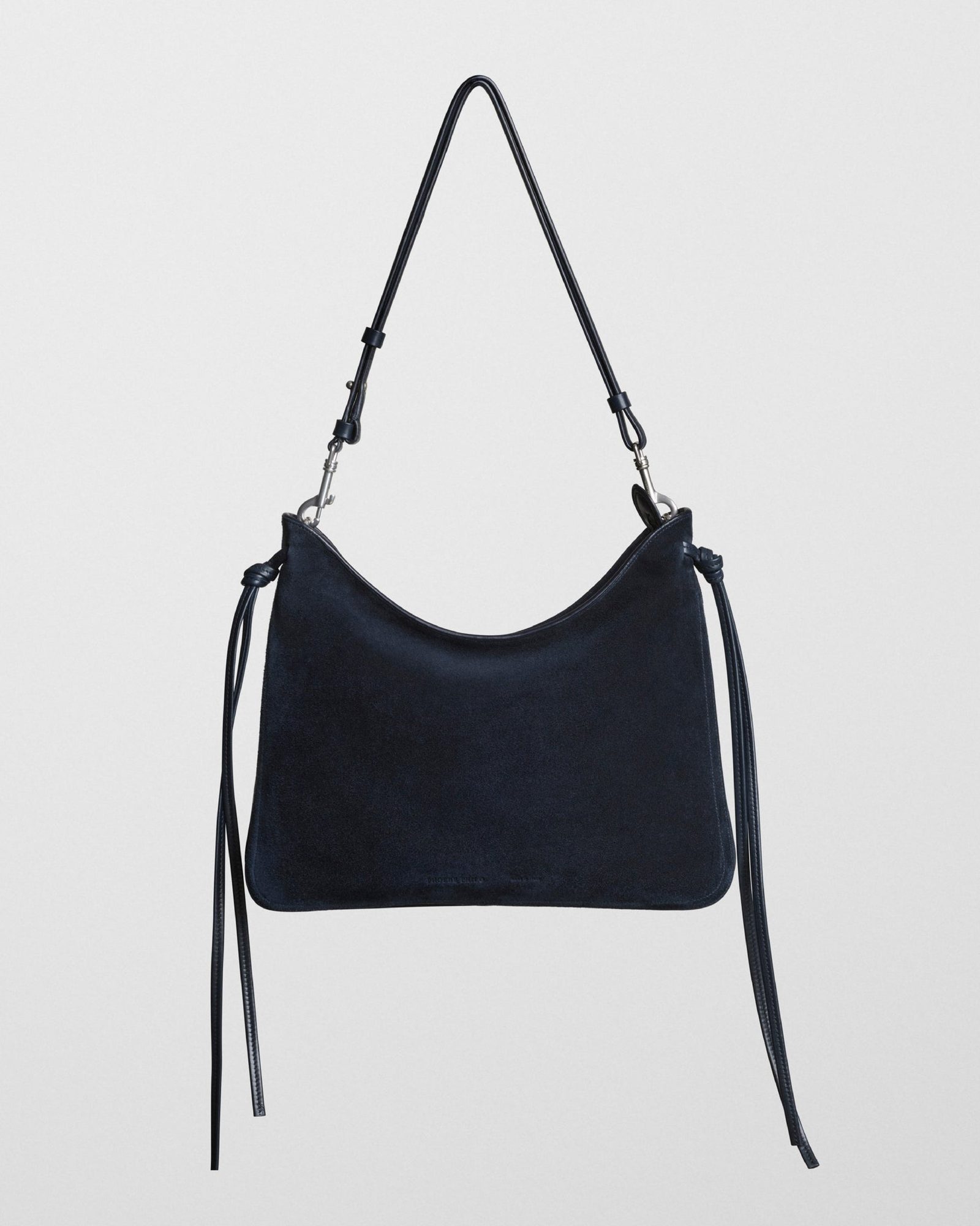Navy suede shoulder bag with adjustable straps and silver hardware against white background