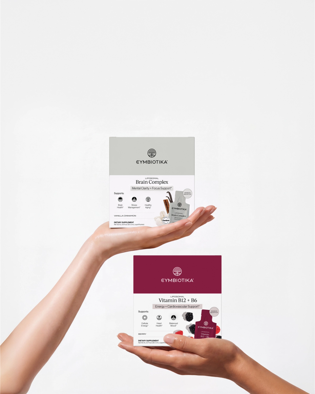 Two hands holding dietary supplement packets for brain complex and vitamin B12+B6