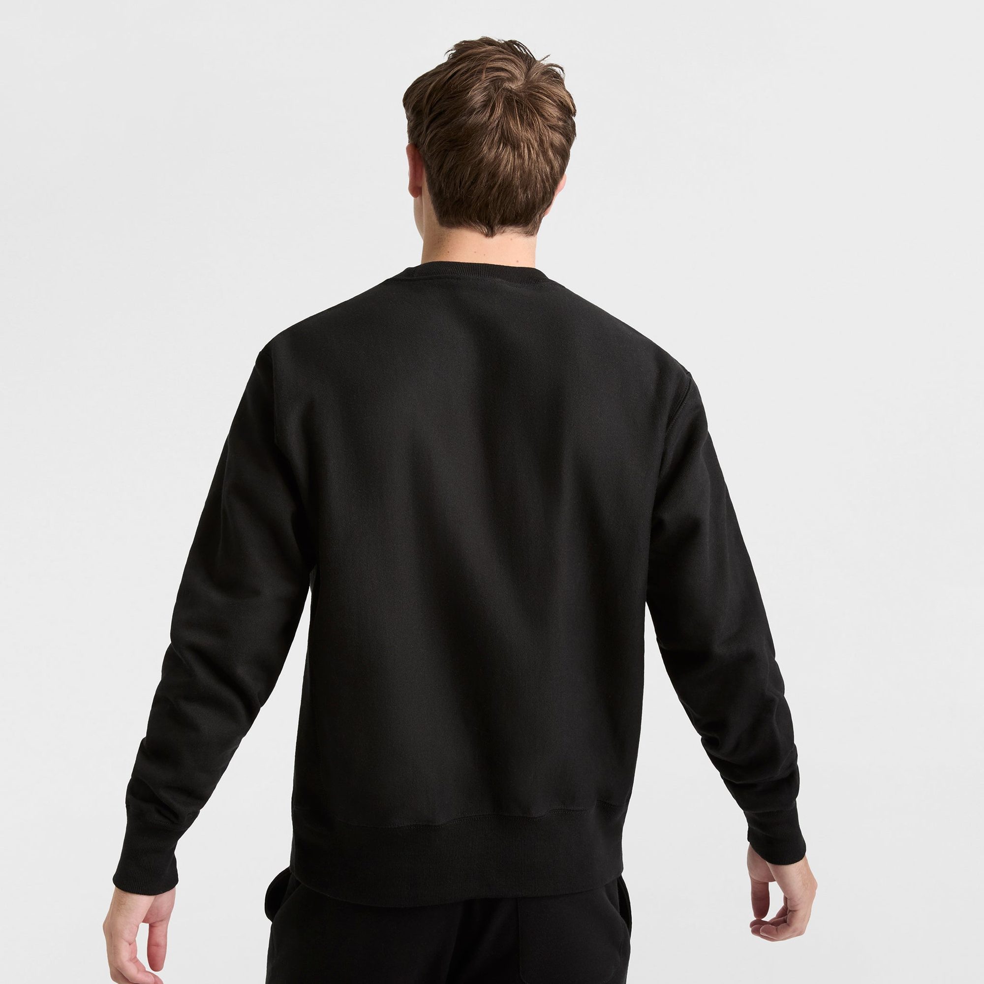 Man wearing black crewneck sweatshirt, shown from back view
