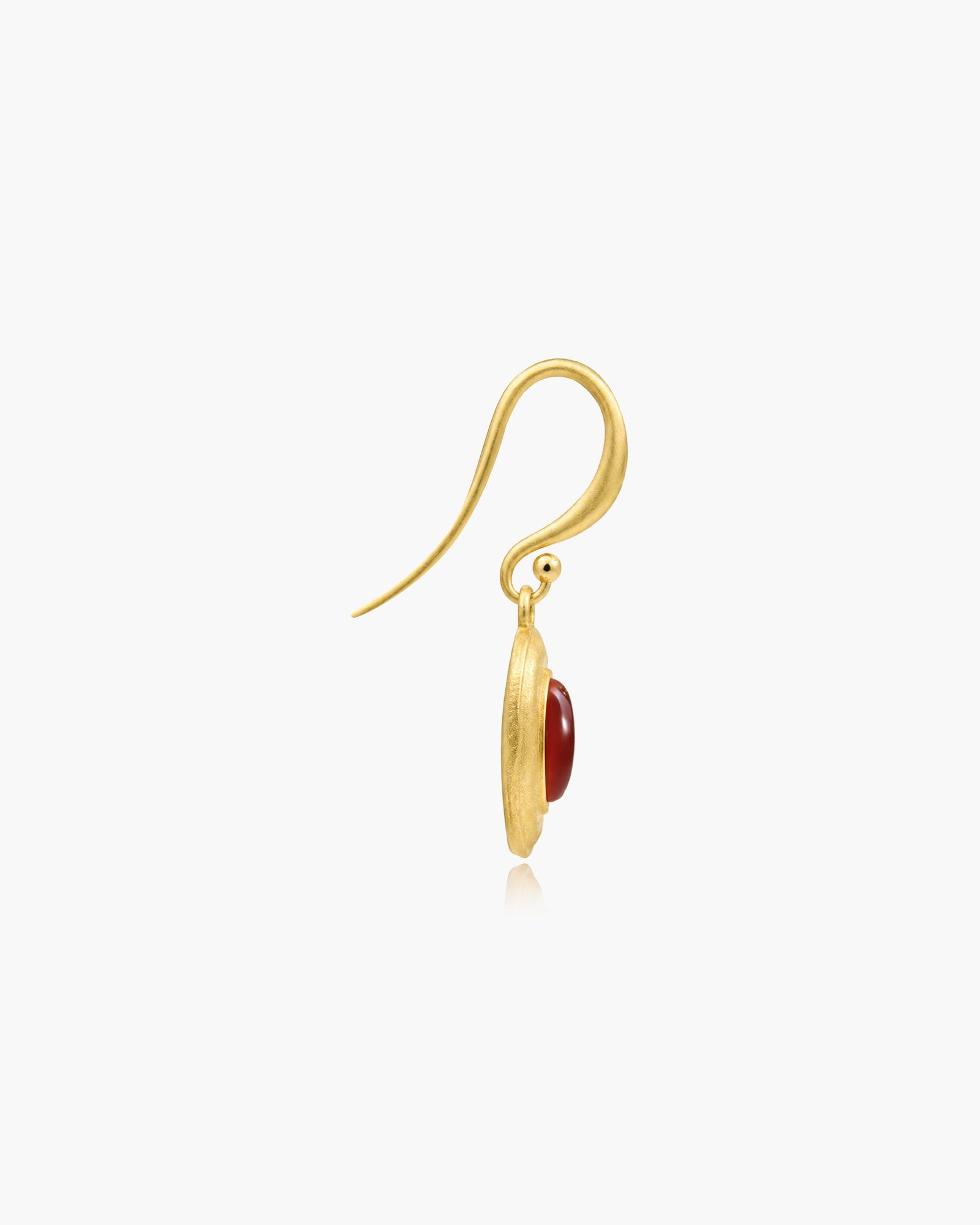 Gold fish hook earring with red oval stone pendant on white background