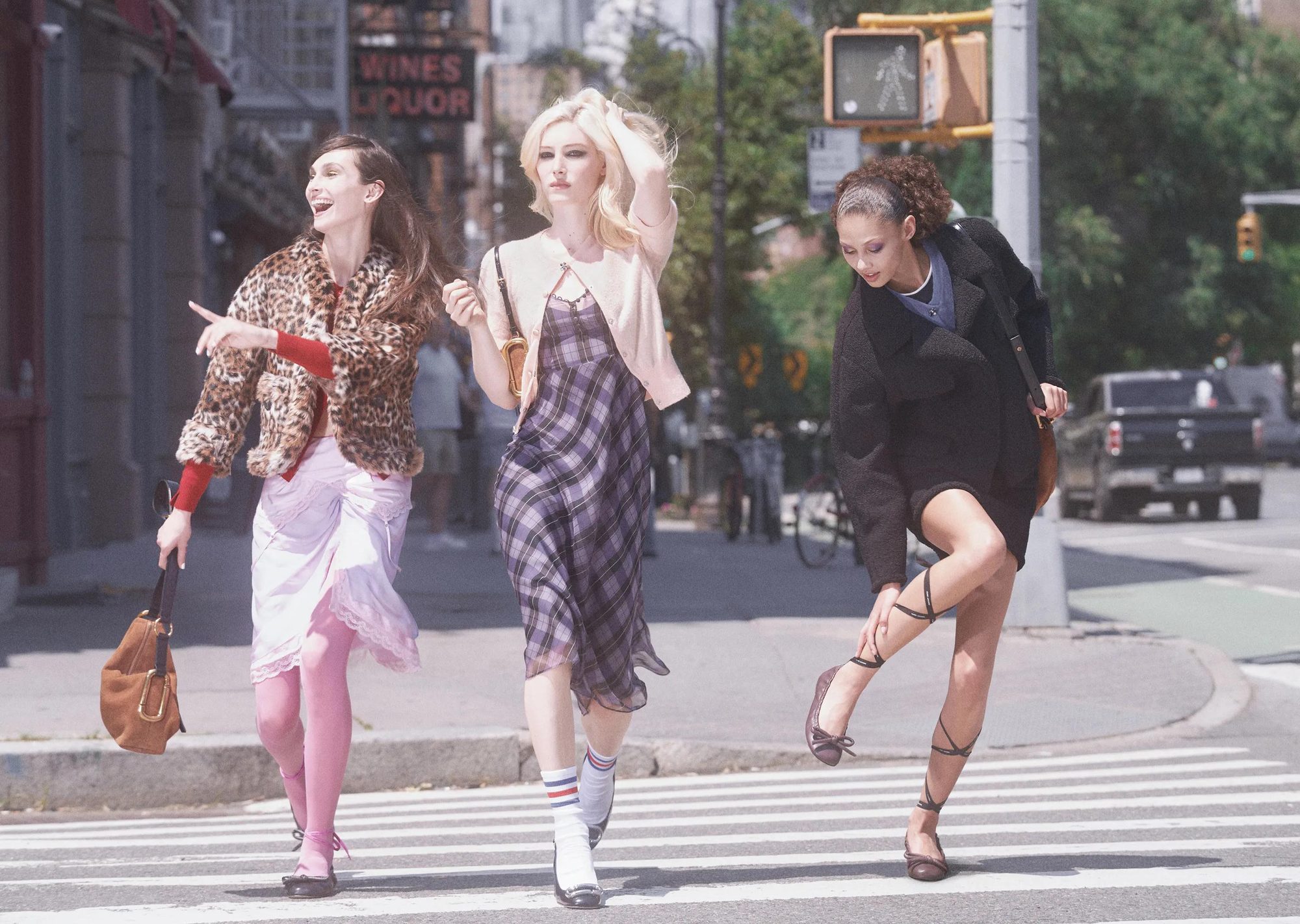 Three women crossing a city street wearing colorful vintage-inspired outfits with 1990s styling