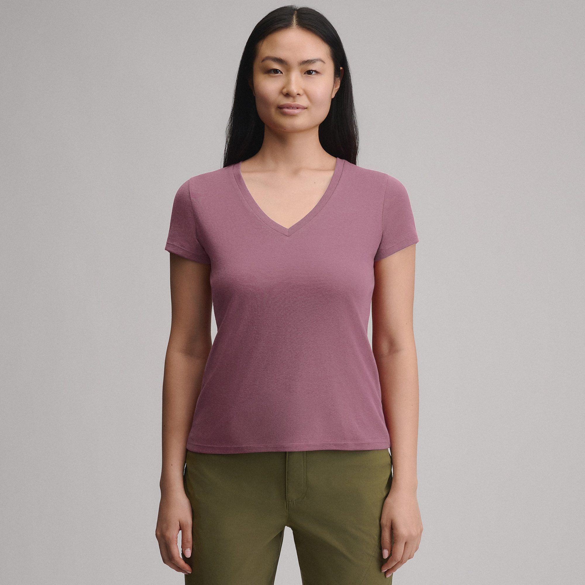 Woman wearing mauve v-neck t-shirt with olive green pants, front view against gray background