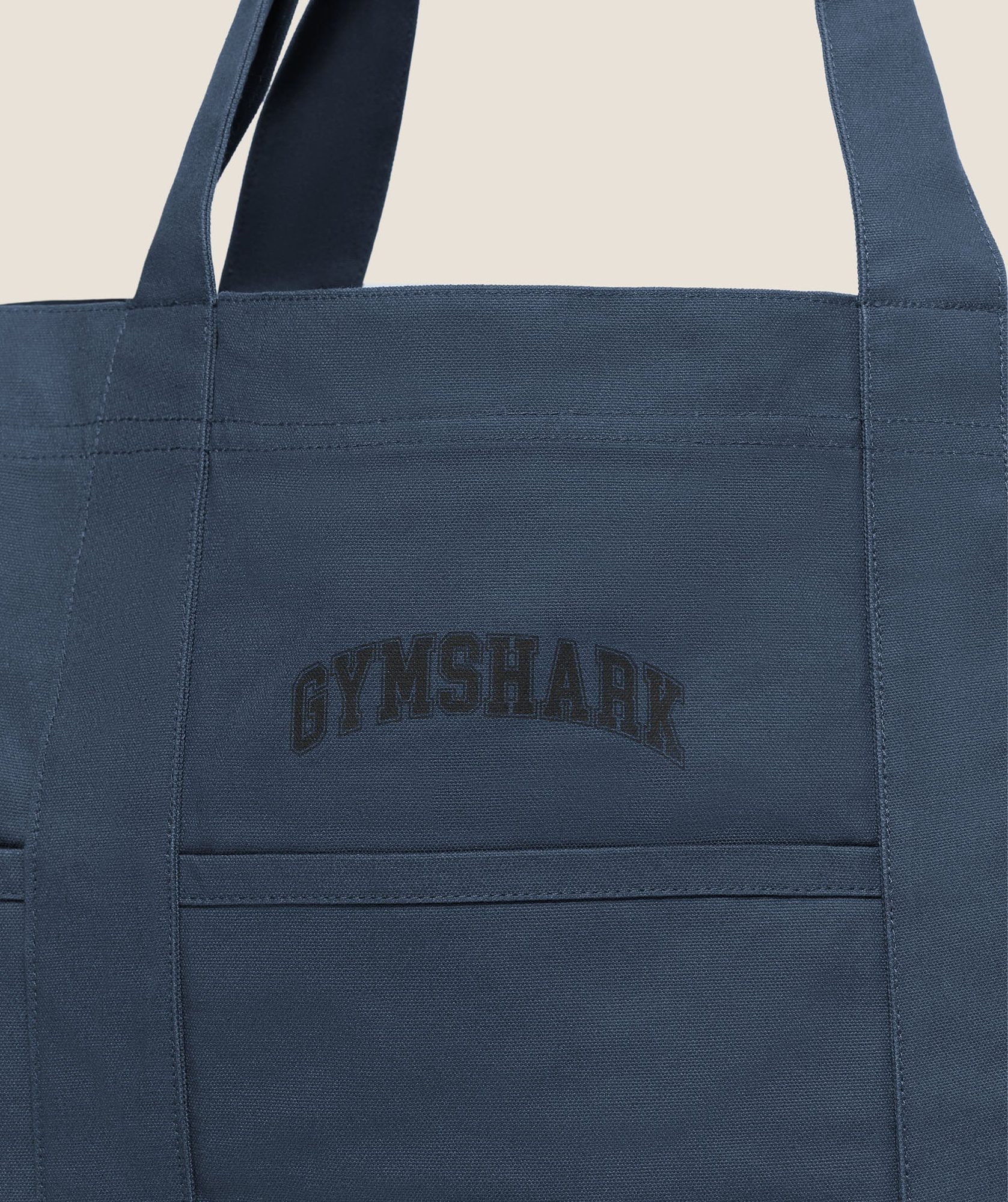 Navy canvas tote bag with embossed branding and horizontal seam detail