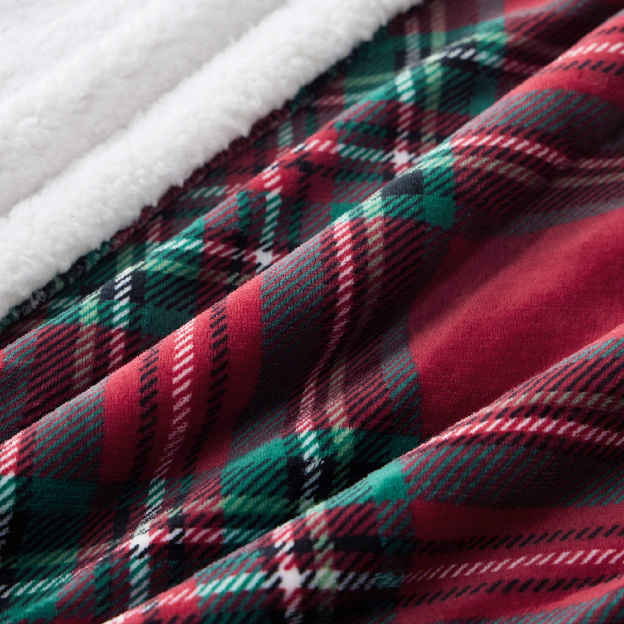 Close-up of red, green, and white plaid flannel fabric texture with soft white fleece backing