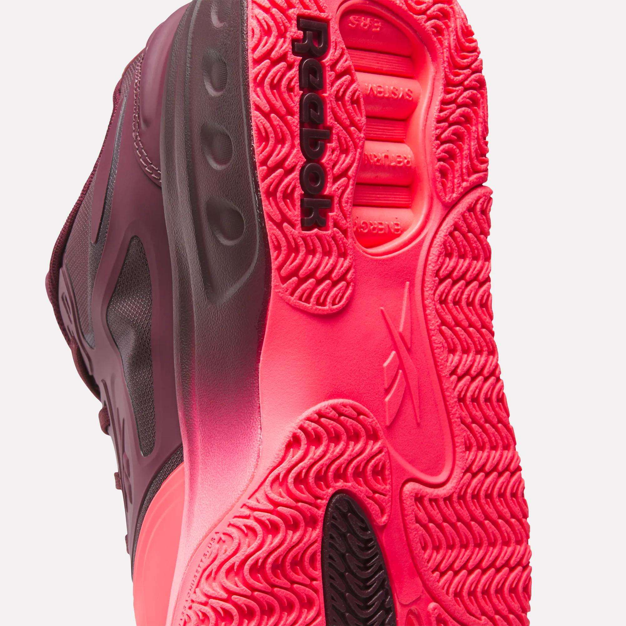 Close-up of shoe soles showing textured neon pink sole pattern and burgundy upper material