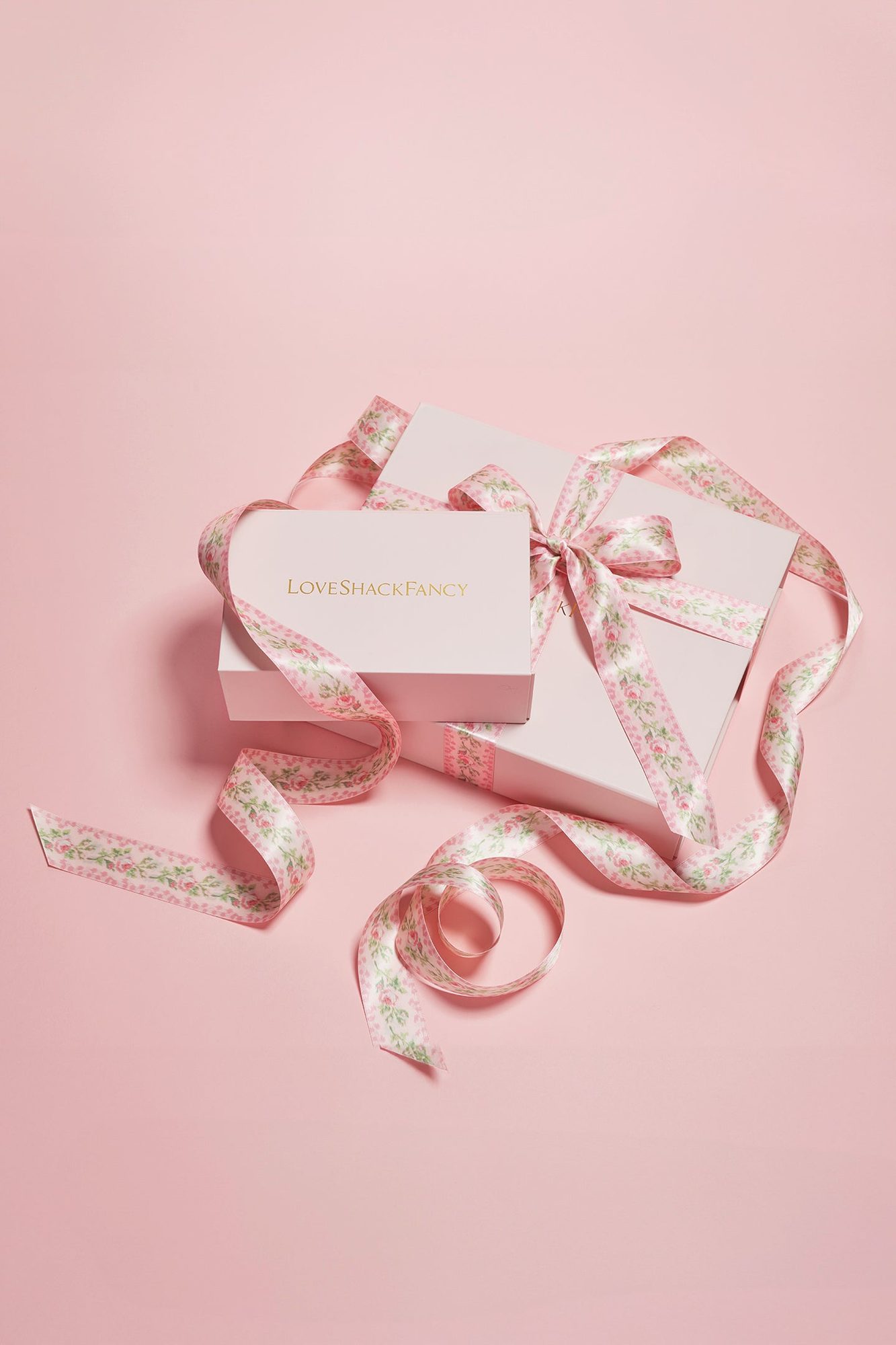 Unwrapped gift box with floral ribbon and white card with gold text