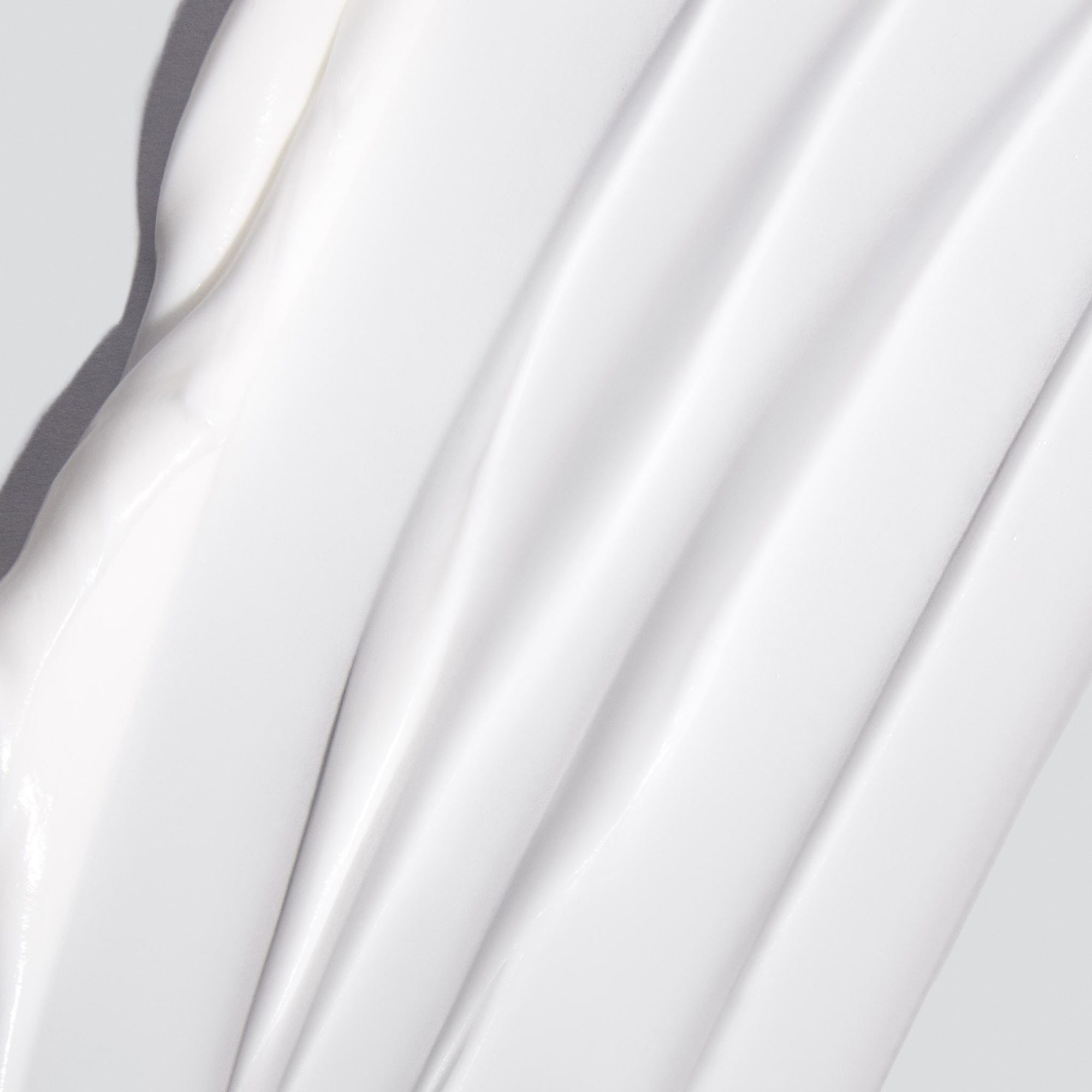 Close-up of smooth white cream texture with diagonal ridges and shadows