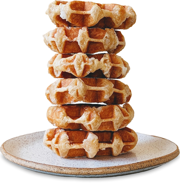Stack of six golden waffles with grid pattern on a speckled plate