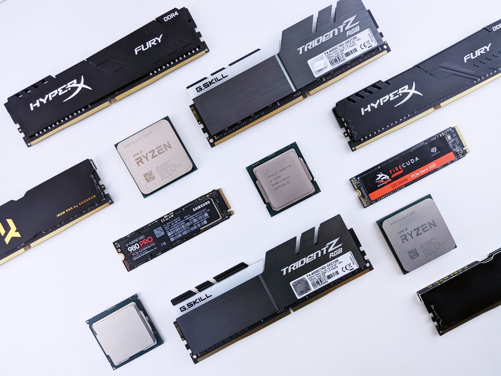 Collection of computer components including RAM modules, processors, M.2 SSDs, and storage drives arranged on white background