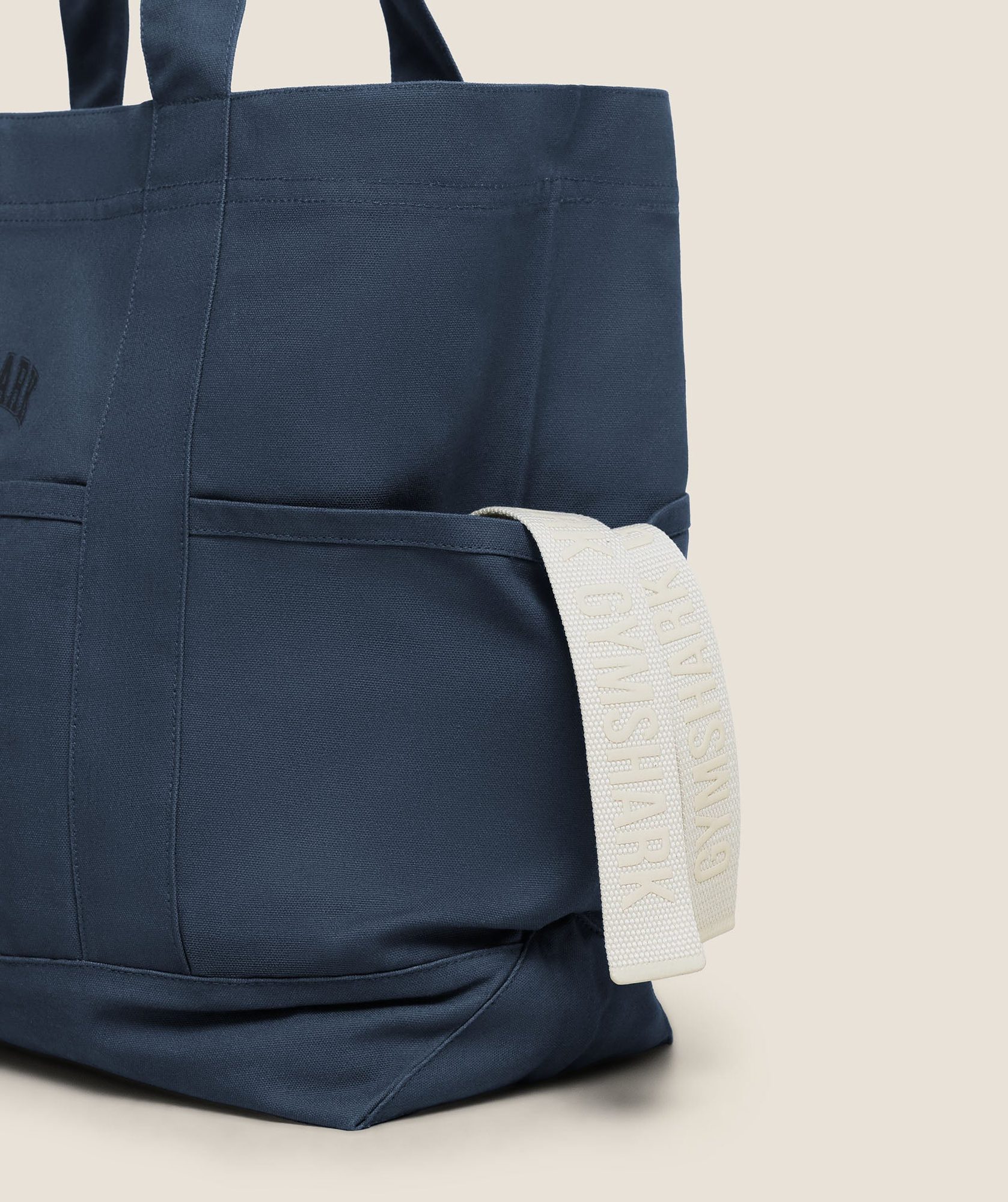 Navy tote bag with white webbing strap accent visible on the side