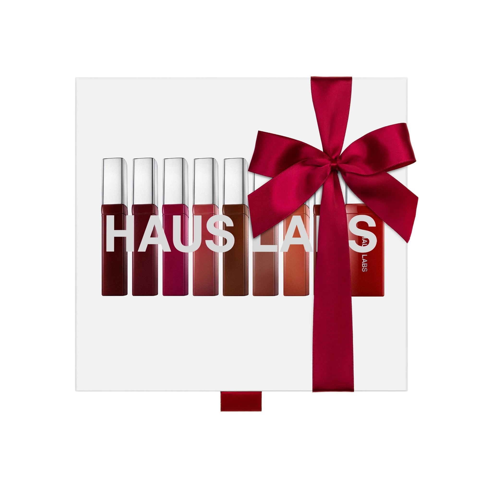 Display of nine liquid lipstick tubes in varying shades from deep burgundy to coral, tied with a large red satin bow