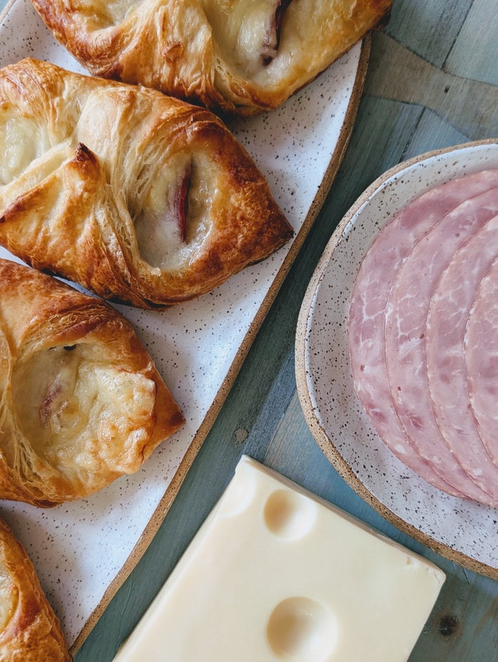Croissants and sliced deli meat with cheese on speckled plates