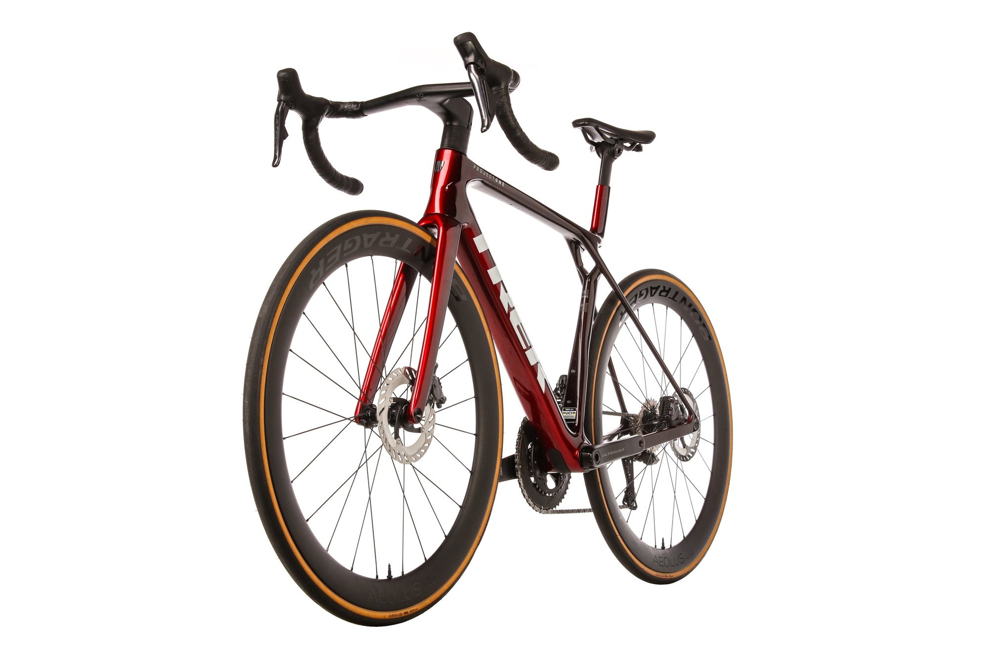 Red and maroon gravel bike with gold-rimmed wheels photographed from rear three-quarter angle