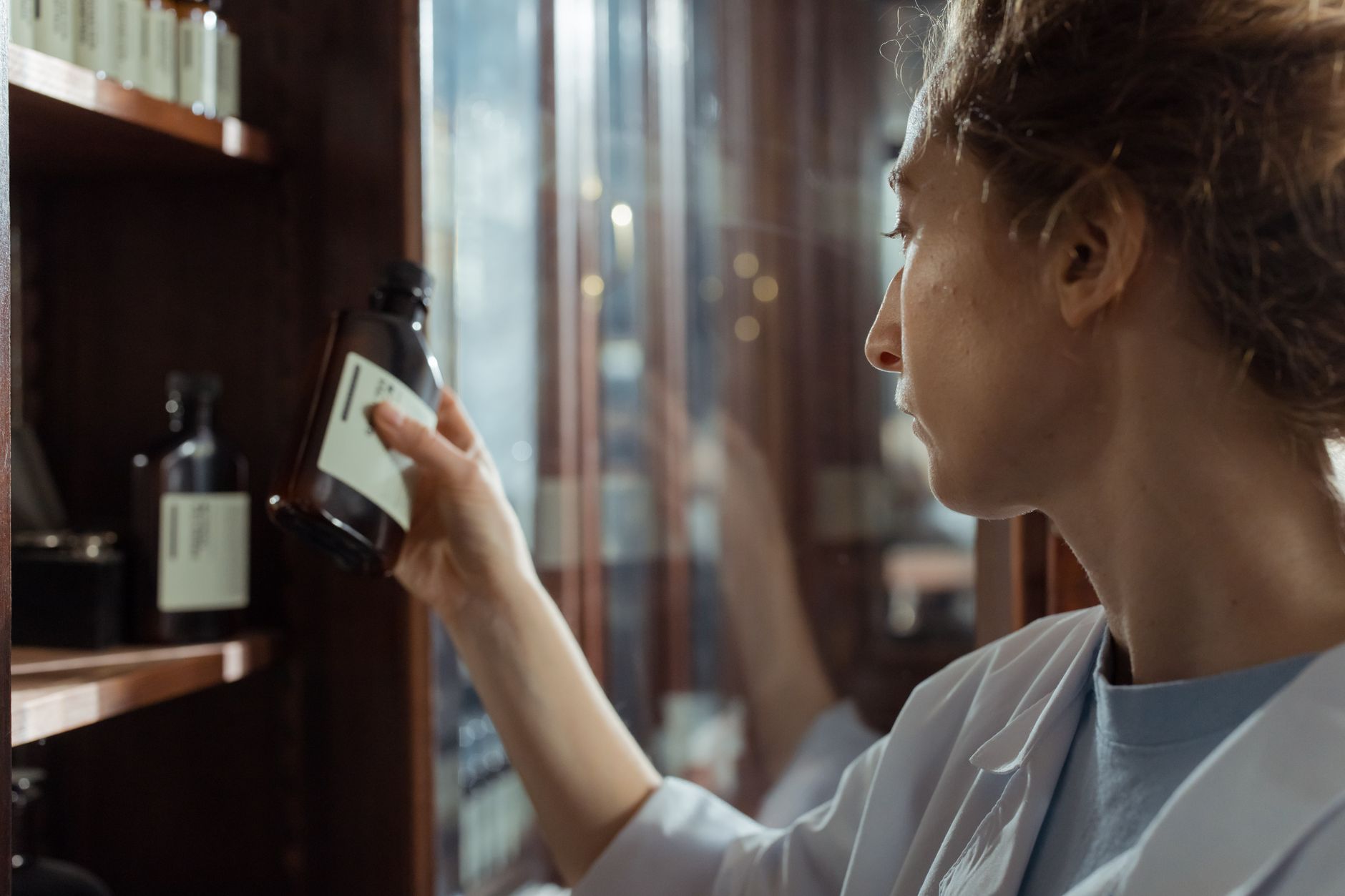Person examining a bottle on a store shelf with blurred retail display in background