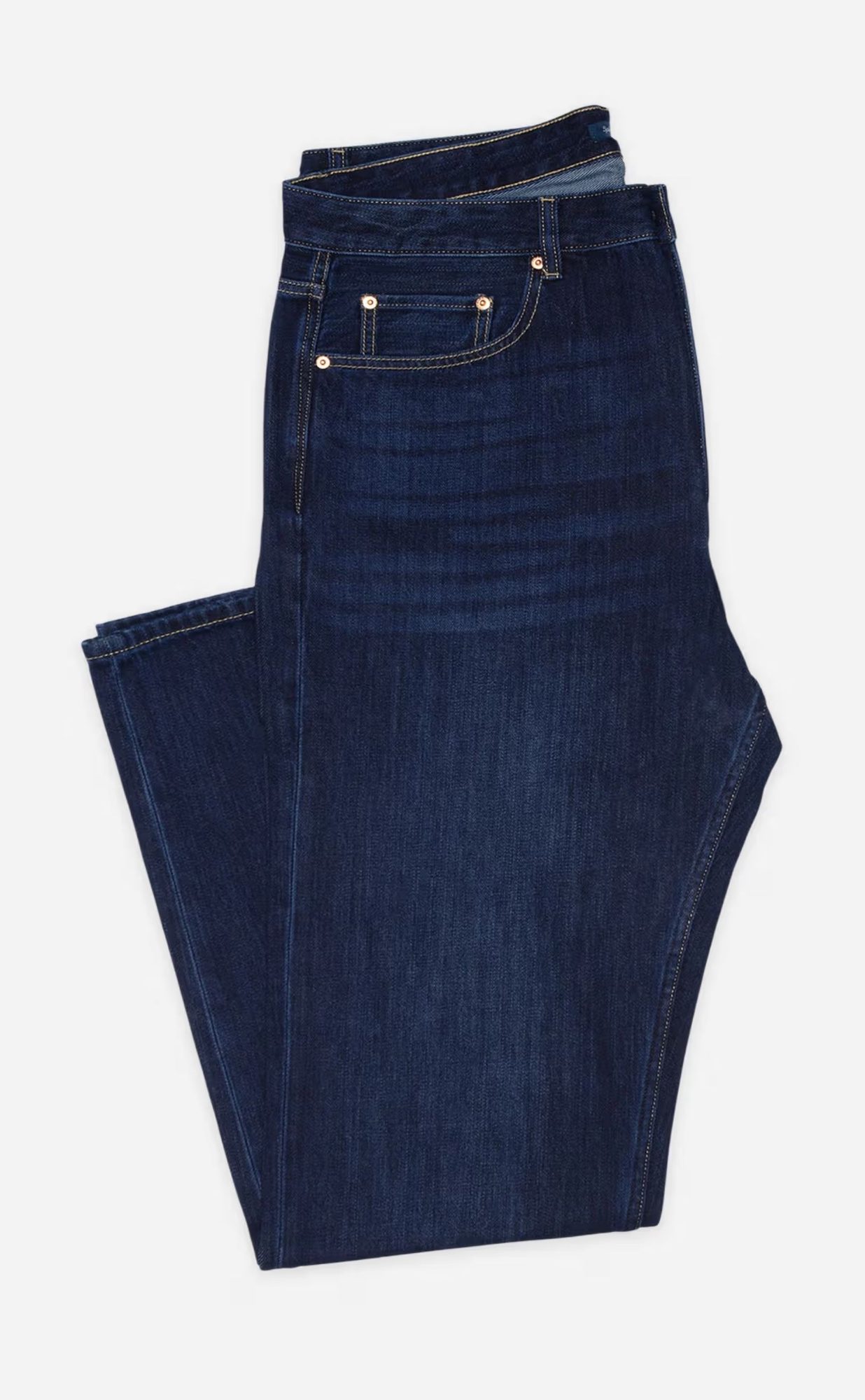 Dark indigo denim jeans folded flat on gray background, showing classic five-pocket construction