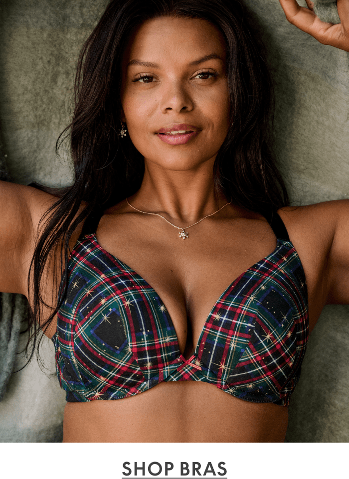 Woman with long dark hair wearing red plaid bra with gold star pattern against gray textured background