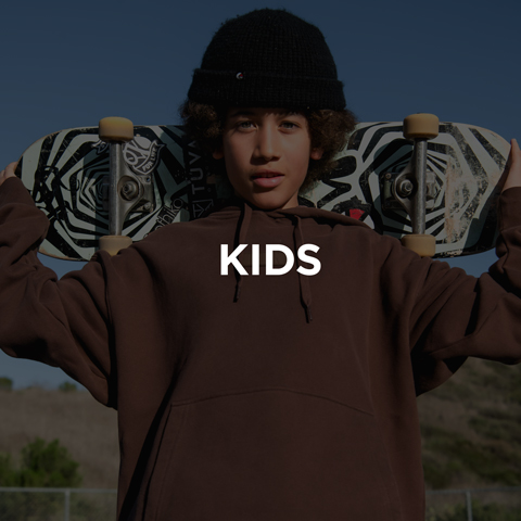 Child holding skateboard wearing brown hoodie and black beanie