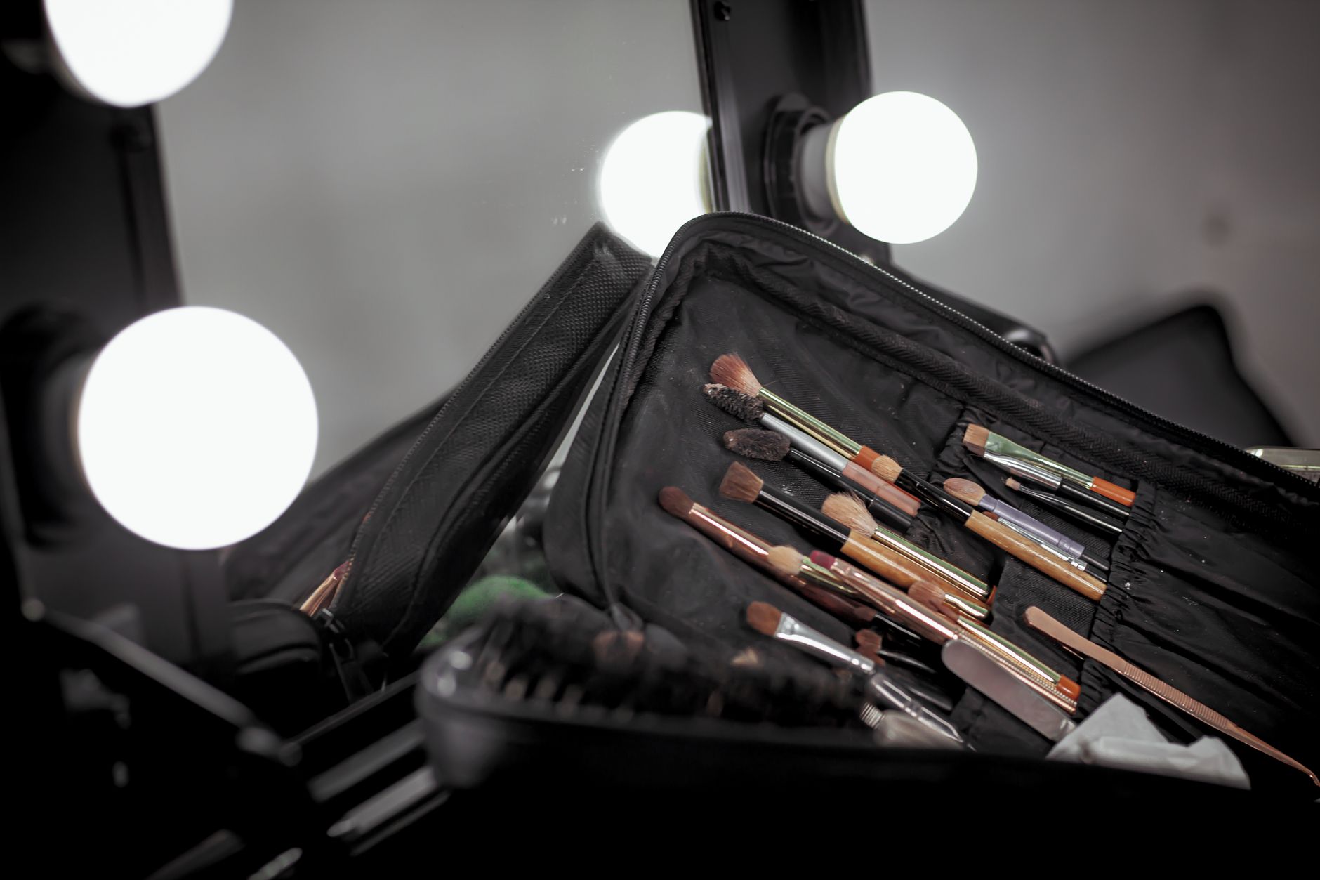 Black makeup brush set in organizer case under vanity mirror lights