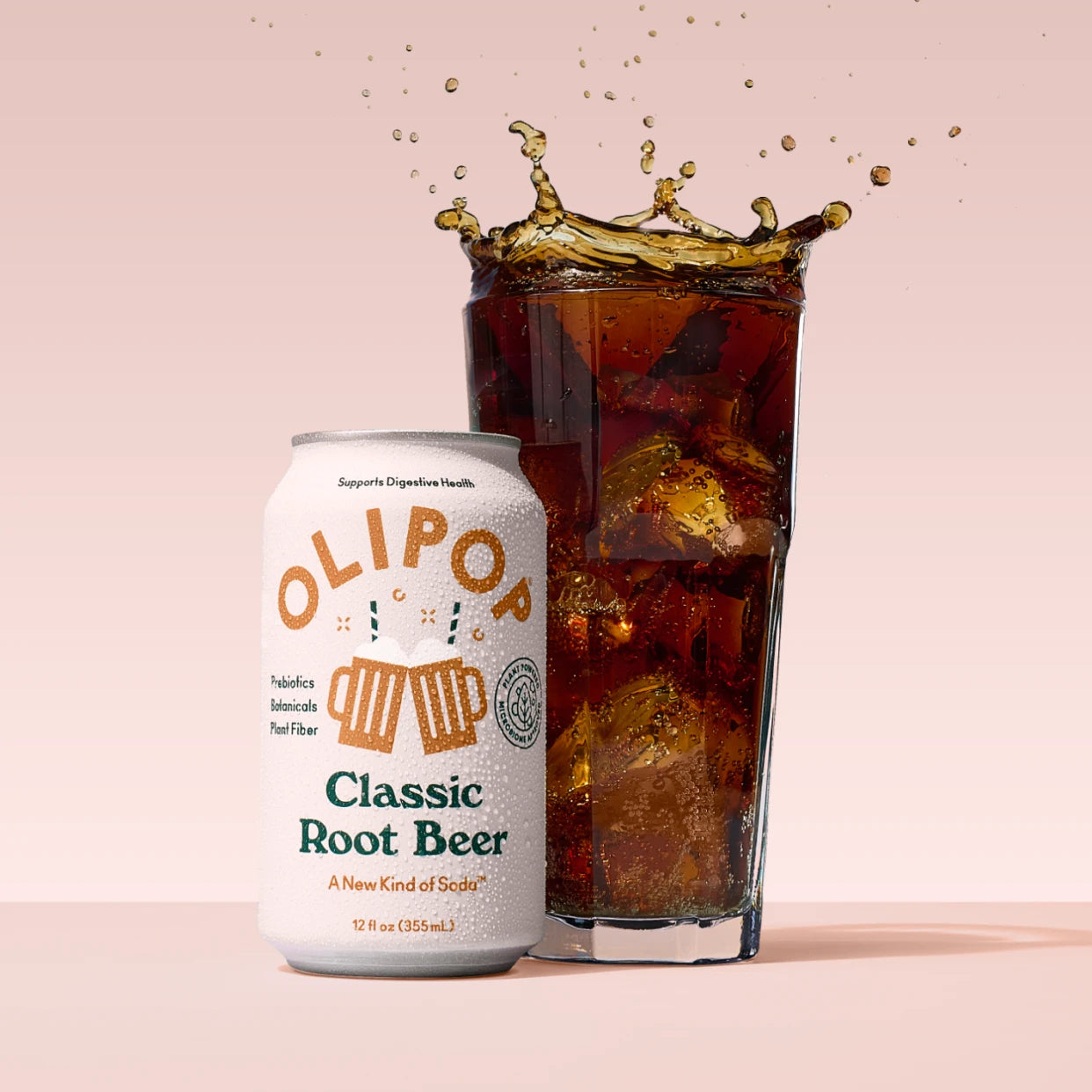 White aluminum can of Classic Root Beer next to a tall glass filled with dark cola and ice with liquid splashing