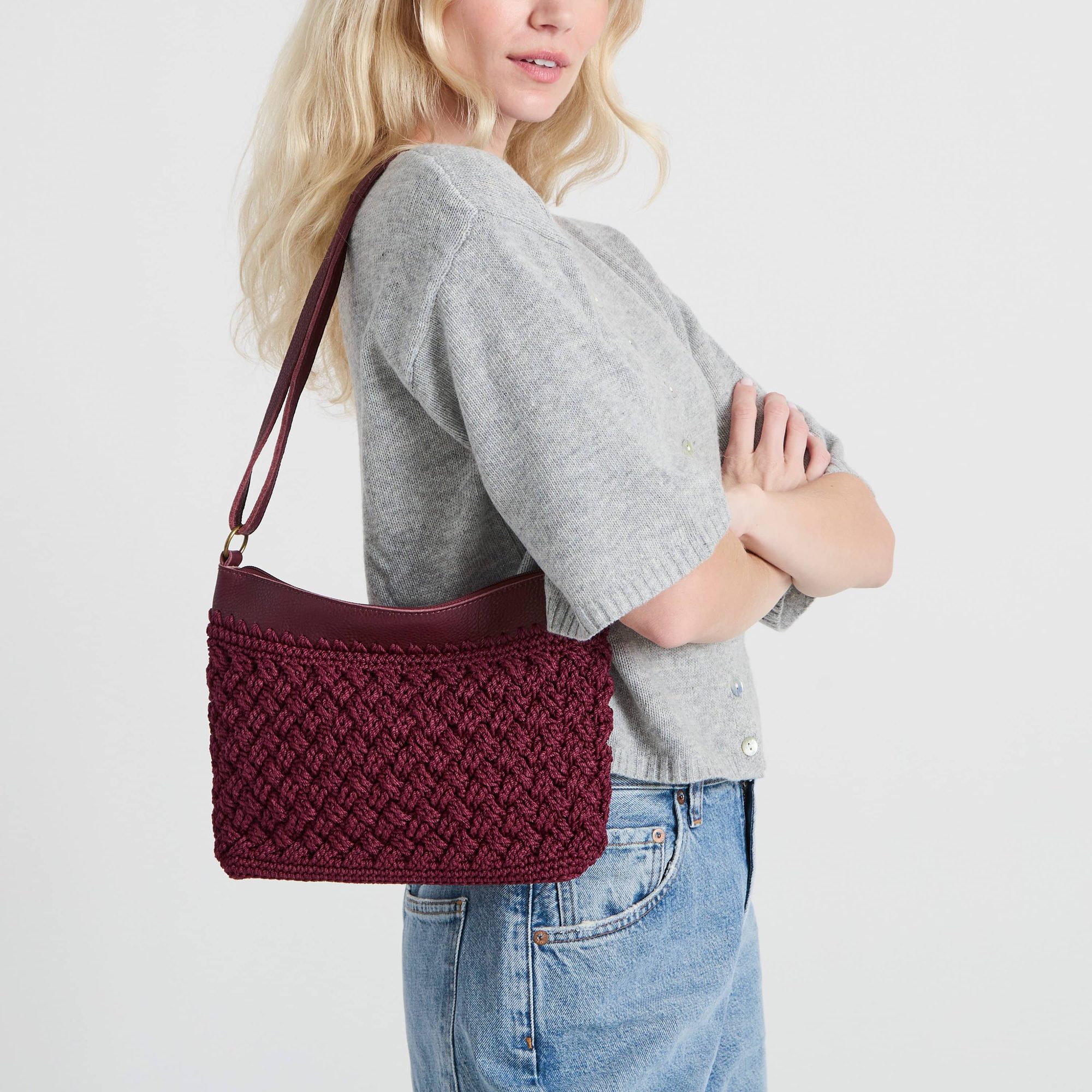 Woman wearing gray cardigan with burgundy quilted crossbody bag