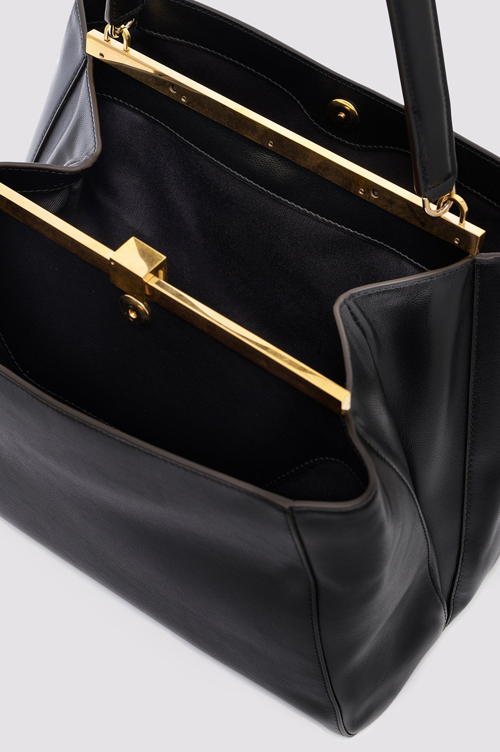 Close-up of black leather bag interior showing gold metal frame and hardware details