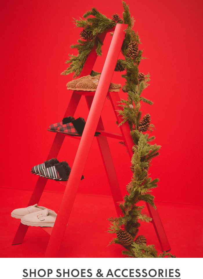 Red ladder decorated with garland and pinecones displaying shoes and plaid socks against red background