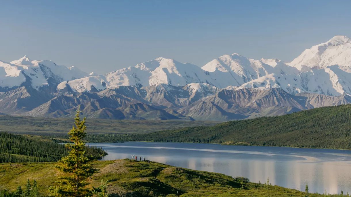 Snow-capped mountain range reflected in pristine lake surrounded by evergreen forest