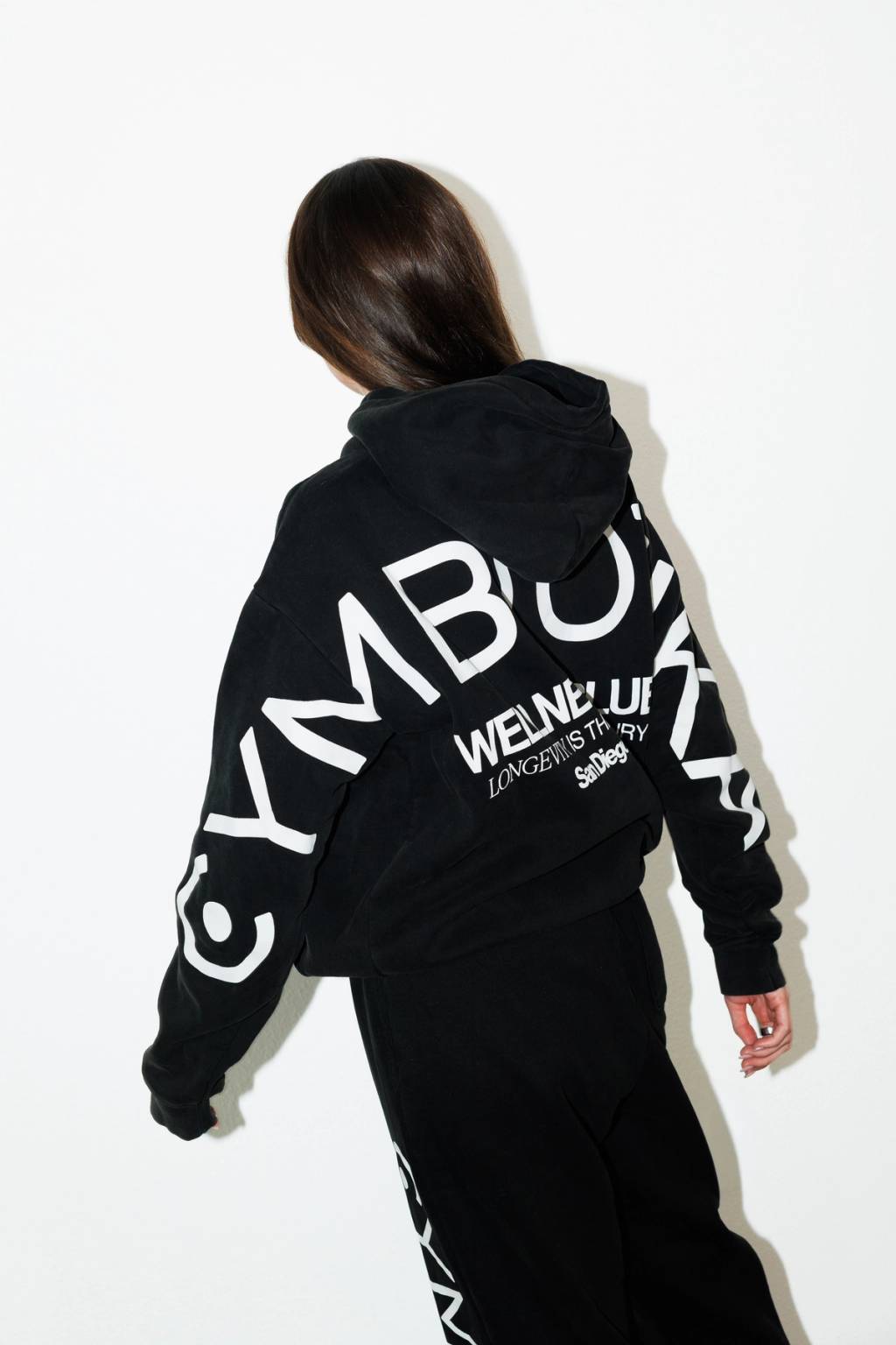 Person wearing black hoodie with white text viewed from behind