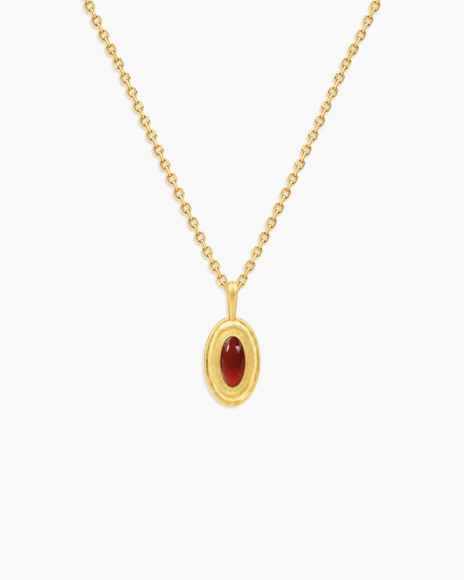 Gold chain necklace with oval pendant featuring red cabochon stone on white background
