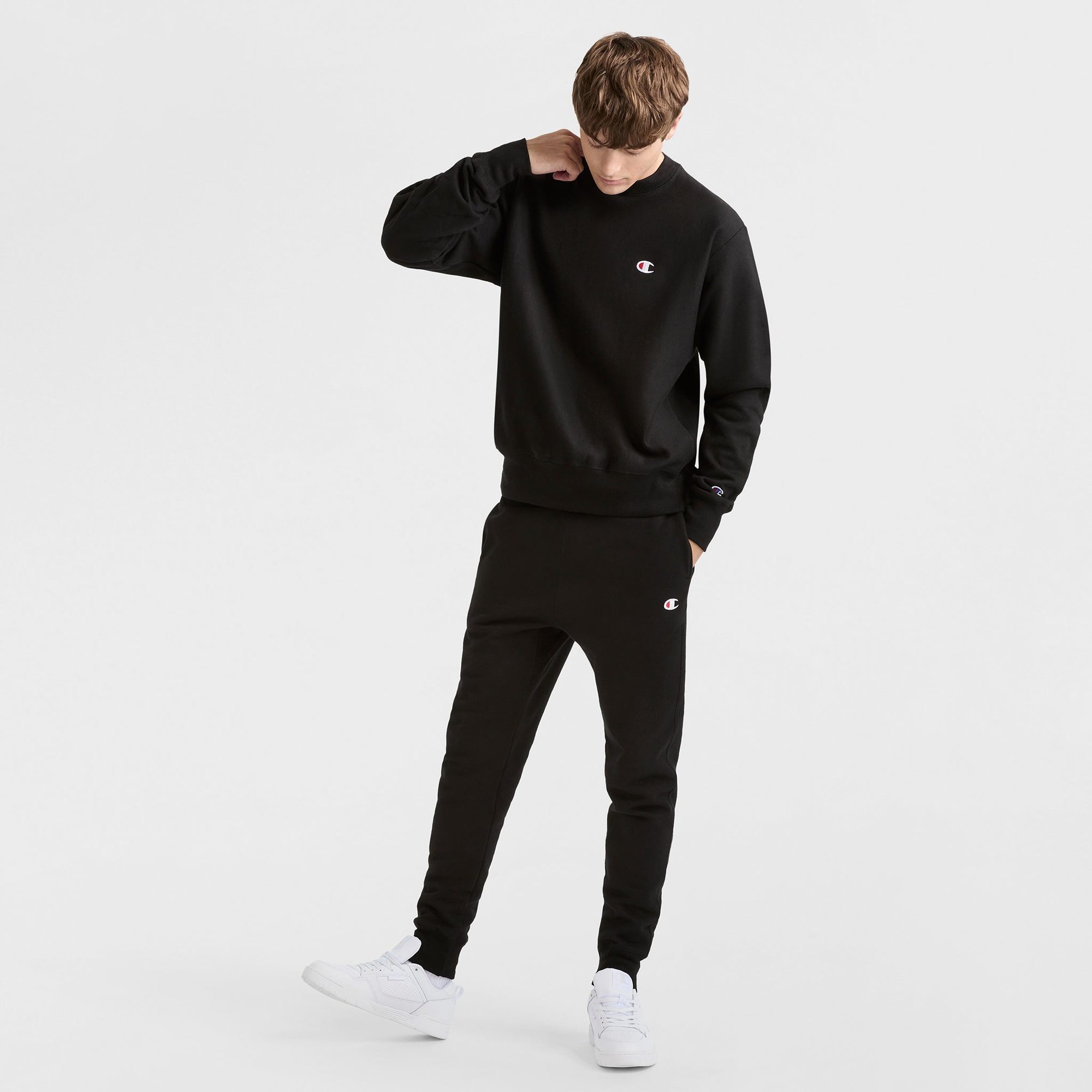 Man wearing black crewneck sweatshirt and matching joggers, full outfit view