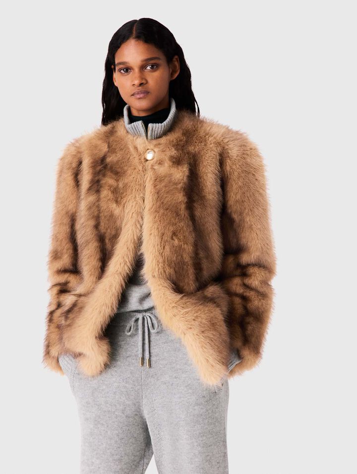 Woman in camel fur jacket with button closure and gray joggers, front view
