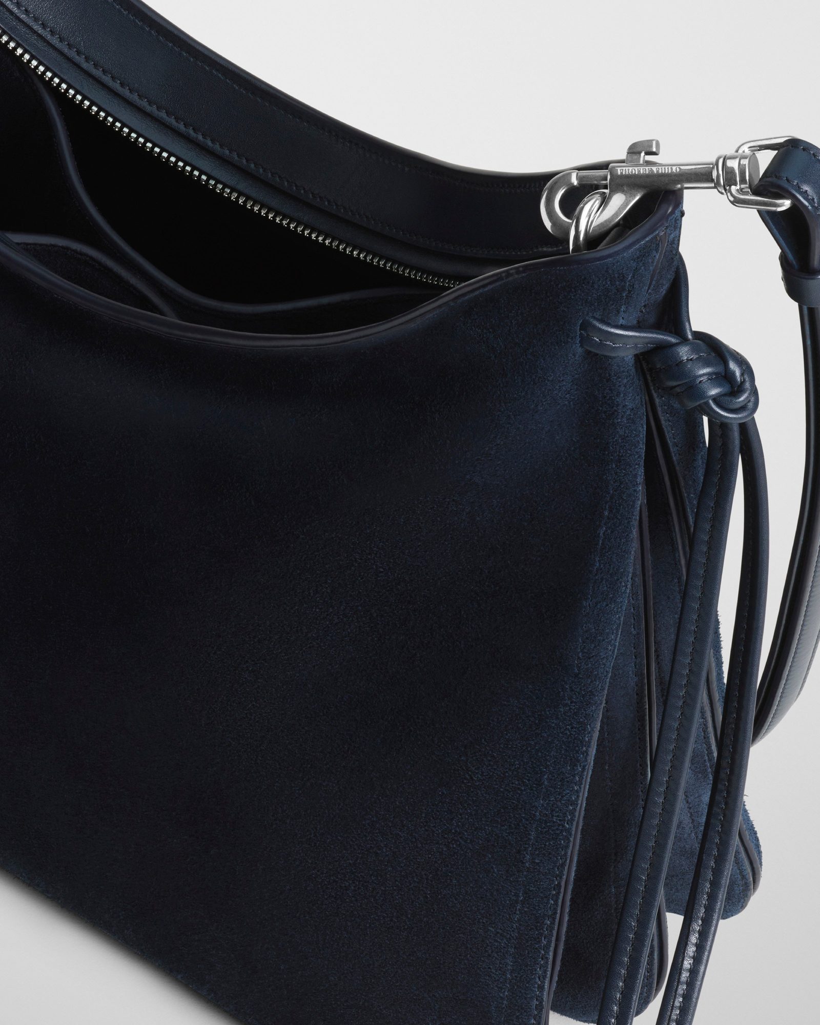 Close-up detail of navy suede bag showing silver clasp hardware and leather fringe accents