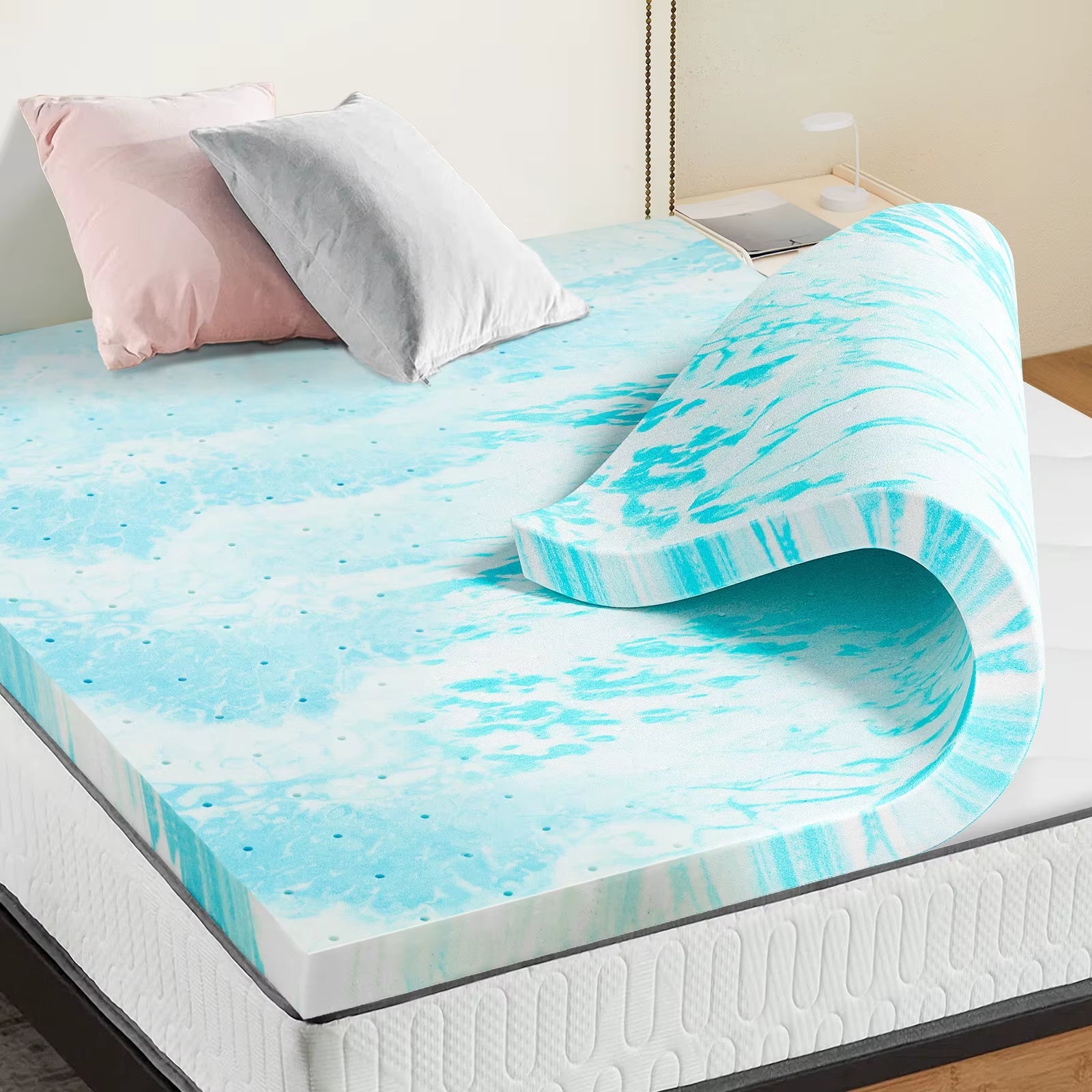 Turquoise and white patterned mattress topper on bed with pink and gray pillows